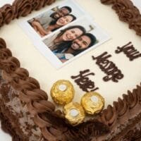 Round personalised photo celebration cake with smooth fresh cream icing, edible photo print, chocolate rosettes, Ferrero Rocher chocolates, chocolate curls and personalised message, handmade by Cake Palace UK.