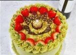 Luxury egg-free pistachio fresh cream cake with fresh strawberries, crushed pistachios, Ferrero Rocher chocolate, and chocolate leaf decorations