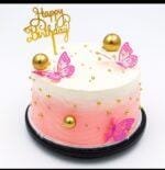 Round Egg Free pink ombre celebration cake decorated with butterfly toppers, edible gold pearls, gold spheres and a Happy Birthday topper.