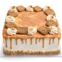 Square fresh cream caramel cake with a rich caramel drip, caramel glaze, fresh cream swirls, and biscuit pieces on top.