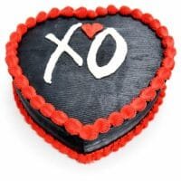 Top view of a heart-shaped black fresh cream cake with red borders and a personalised XO design.