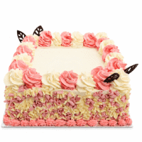 Pink and white celebration cake decorated with whipped frosting swirls, pink and white chocolate curls around the sides, chocolate leaf decorations, and a smooth personalised message area for birthdays and special occasions.