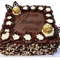 Square chocolate celebration cake with smooth chocolate frosting, Ferrero Rocher chocolates, chocolate leaf decorations, white cream flowers, mixed chocolate curls around the sides, and a personalised message area in the centre.