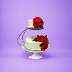 Luxury two-tier fresh cream wedding cake with red rose floral decoration on floating cake stand